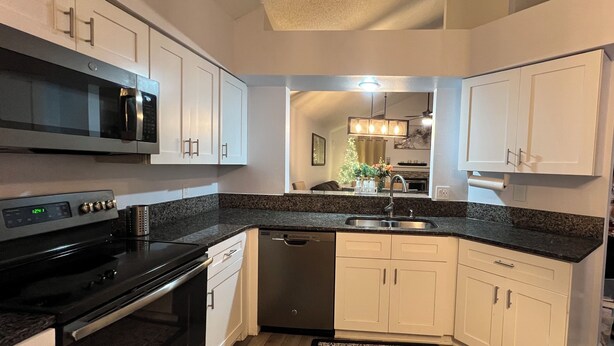 A modern kitchen with white cabinets, a black stove, a dishwasher, and a granite countertop. - Near universal studios Charming 4bed house with WiFi, AC in enjoyable Orlando (Orlando)