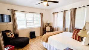 A bedroom with a bed, a desk, a chair, a ceiling fan, and a window with curtains. - Hearts Cottage Waterfront Caddo Big Cypress River (Karnack)