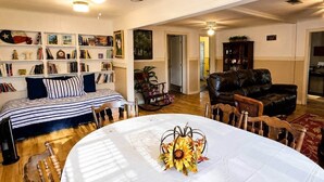 A living room with a dining table, a sofa, a bookshelf, and a fireplace. - Hearts Cottage Waterfront Caddo Big Cypress River (Karnack)