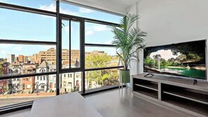 Un salon moderne avec de grandes fenêtres, un téléviseur à écran plat et une plante en pot.