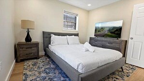 A bedroom with a bed, a nightstand, a lamp, a television, and a window. - Warm and Bright Home | Metro | 1 Min Walk | Md (Capitol Heights)