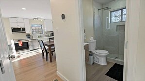 A modern kitchen with a dining area, a separate bathroom with a shower, and a visible door leading to another room. - Warm and Bright Home | Metro | 1 Min Walk | Md (Capitol Heights)