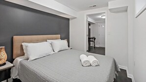 A modern hotel room with a large bed, a nightstand, and a mirror. - Private Capitol Heights Guest Suite near Metro with Laundry (Capitol Heights)