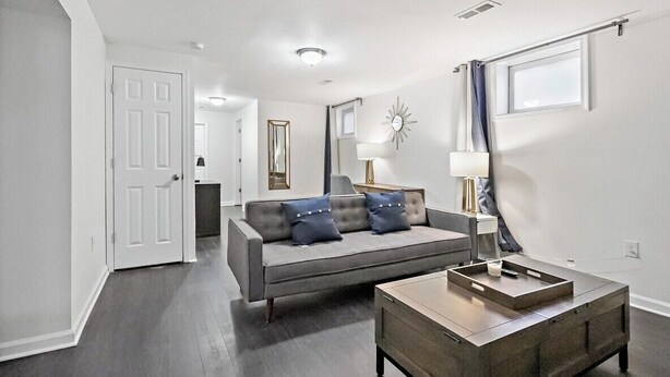 A modern living room with a grey sofa, a wooden coffee table, and a chandelier. - Private Capitol Heights Guest Suite near Metro with Laundry (Capitol Heights)