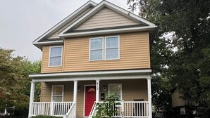 A two-story house with a red front door, a covered porch, and a number '413' on the door. - Arlington | Lower Suite | Center | Efficiency (Arlington)