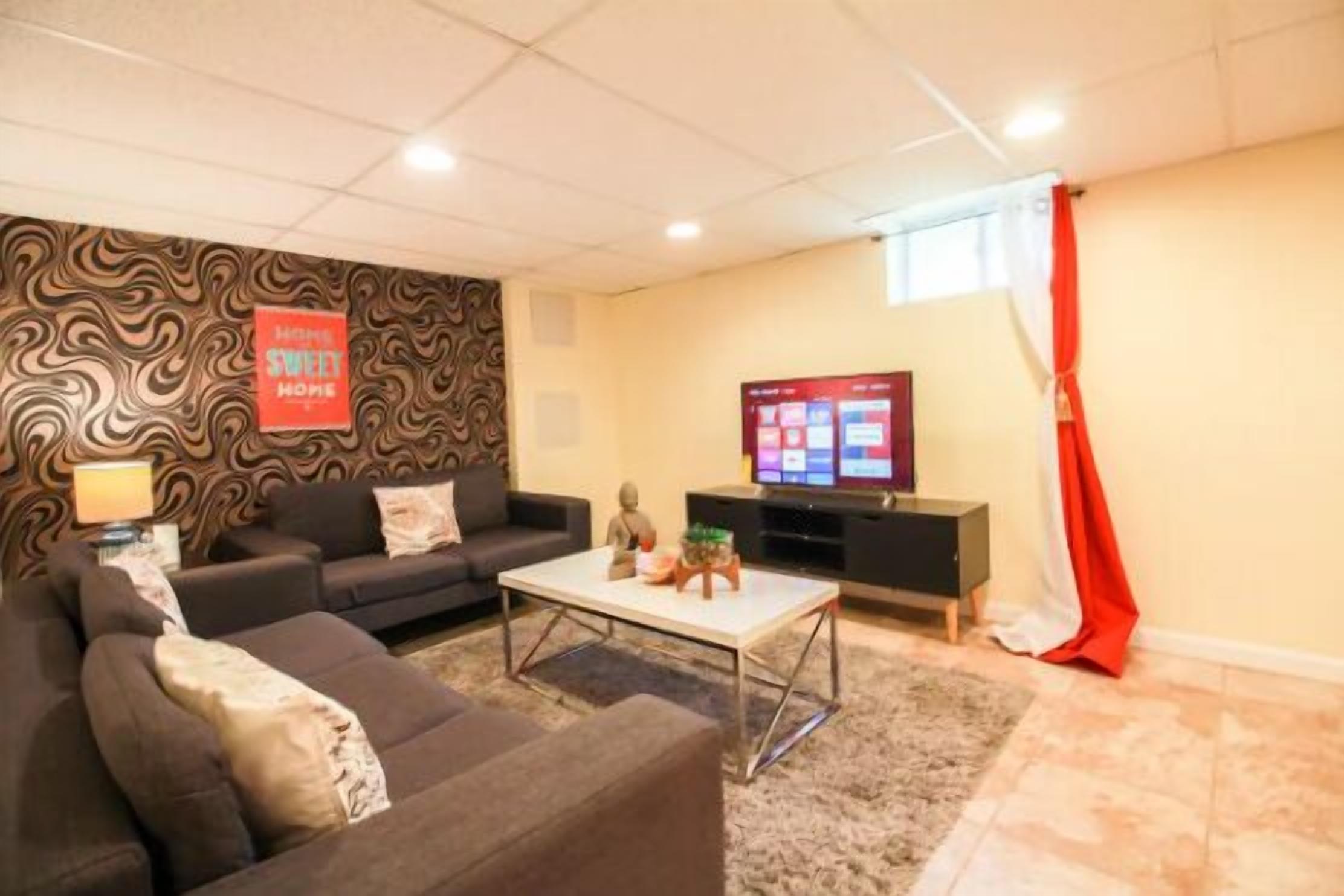 A living room with a sofa, a coffee table, a TV, and a patterned wall.
