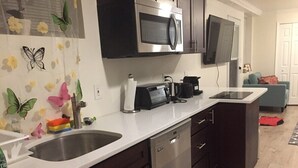 Een moderne keuken met donkere kastjes, roestvrijstalen apparatuur en een wit aanrecht.