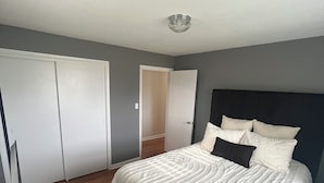 Une chambre à coucher avec un grand lit, une armoire et une porte donnant sur une autre pièce.
