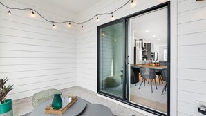 A modern patio with a glass door leading to a kitchen area.