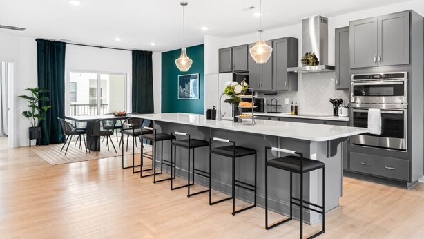 A modern kitchen with a large island, bar stools, and stainless steel appliances.
