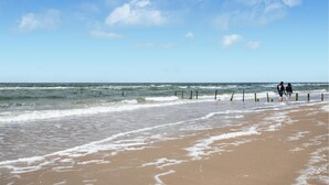 A beach with waves, a clear sky, and two people walking along the shore. - 2 bedroom beautiful home in Rømø (Rømø)