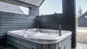 A hot tub with a wooden exterior, a bottle of liquor, and a glass on the edge. - 2 bedroom beautiful home in Rømø (Rømø)