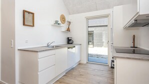 A modern kitchen with white cabinetry, a built-in dishwasher, and a coffee maker on the countertop. - 2 bedroom beautiful home in Rømø (Rømø)