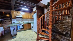 Une cuisine avec des meubles en bois, un mur en pierre et un escalier en bois.