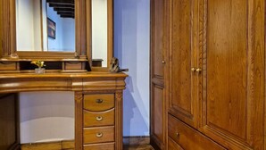 Une coiffeuse en bois avec un miroir, un petit vase et une paire de chaussures.