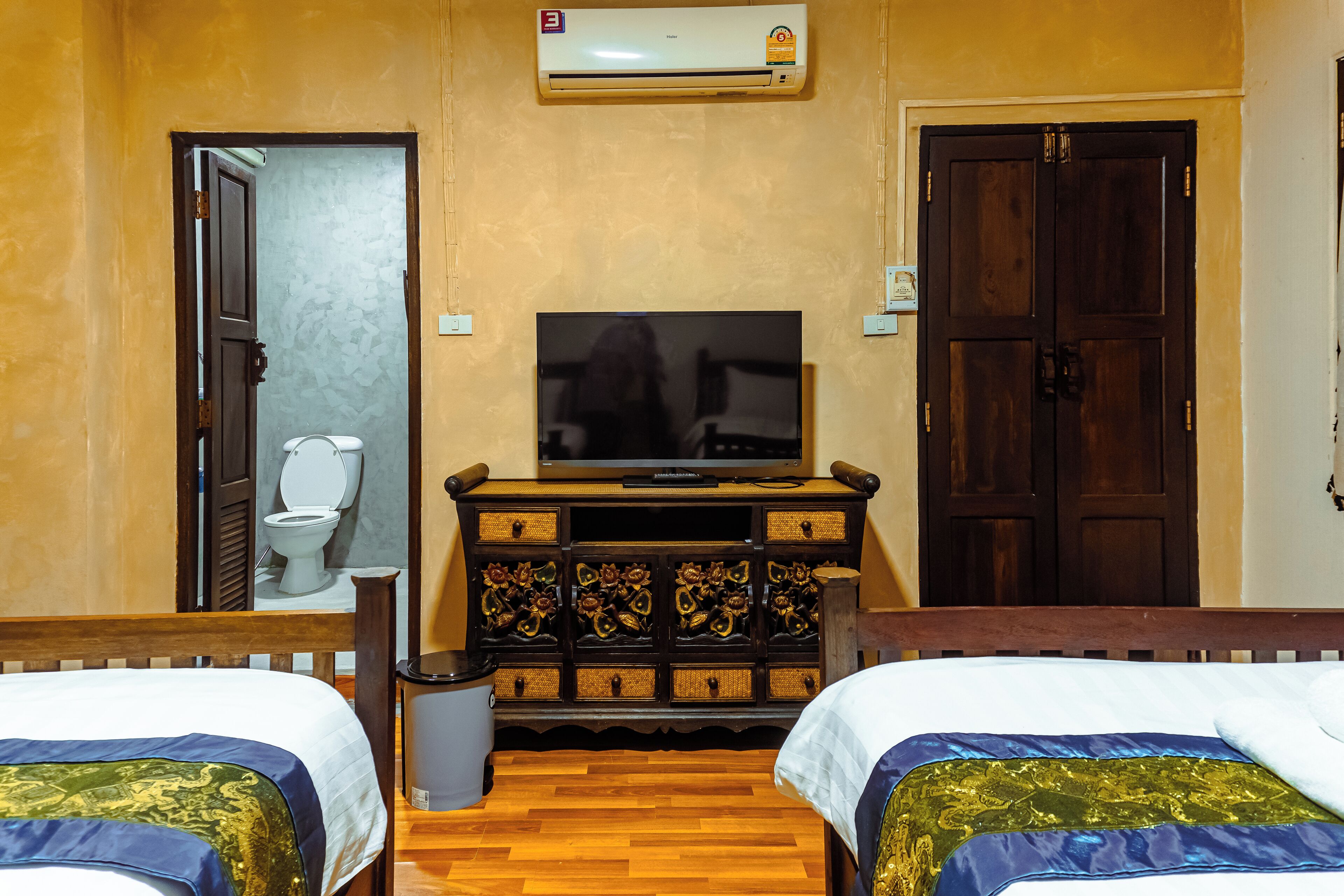 A hotel room with two beds, a television, a wooden dresser, and a bathroom visible through an open door.