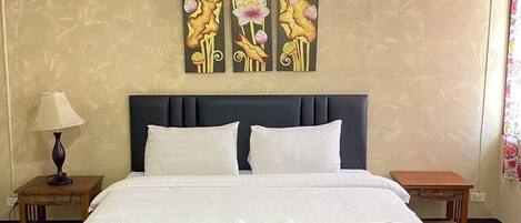 Een hotelkamer met een groot bed, twee nachtkastjes, een schilderij aan de muur en een plafondlamp.