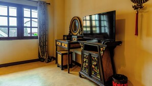 A room with a TV, a decorative cabinet, a small table, and a window with curtains. - EAIN (Chiang Mai)
