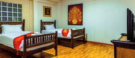 A hotel room with two wooden beds, a television, and a large decorative painting on the wall.