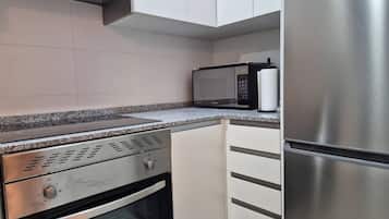 Una cocina equipada con horno empotrado, microondas y refrigerador de acero inoxidable.