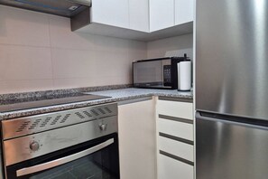 A kitchen with a built-in oven, microwave, and stainless steel refrigerator. - 650A Apartamento moderno, acogedor y con garaje (Oviedo)