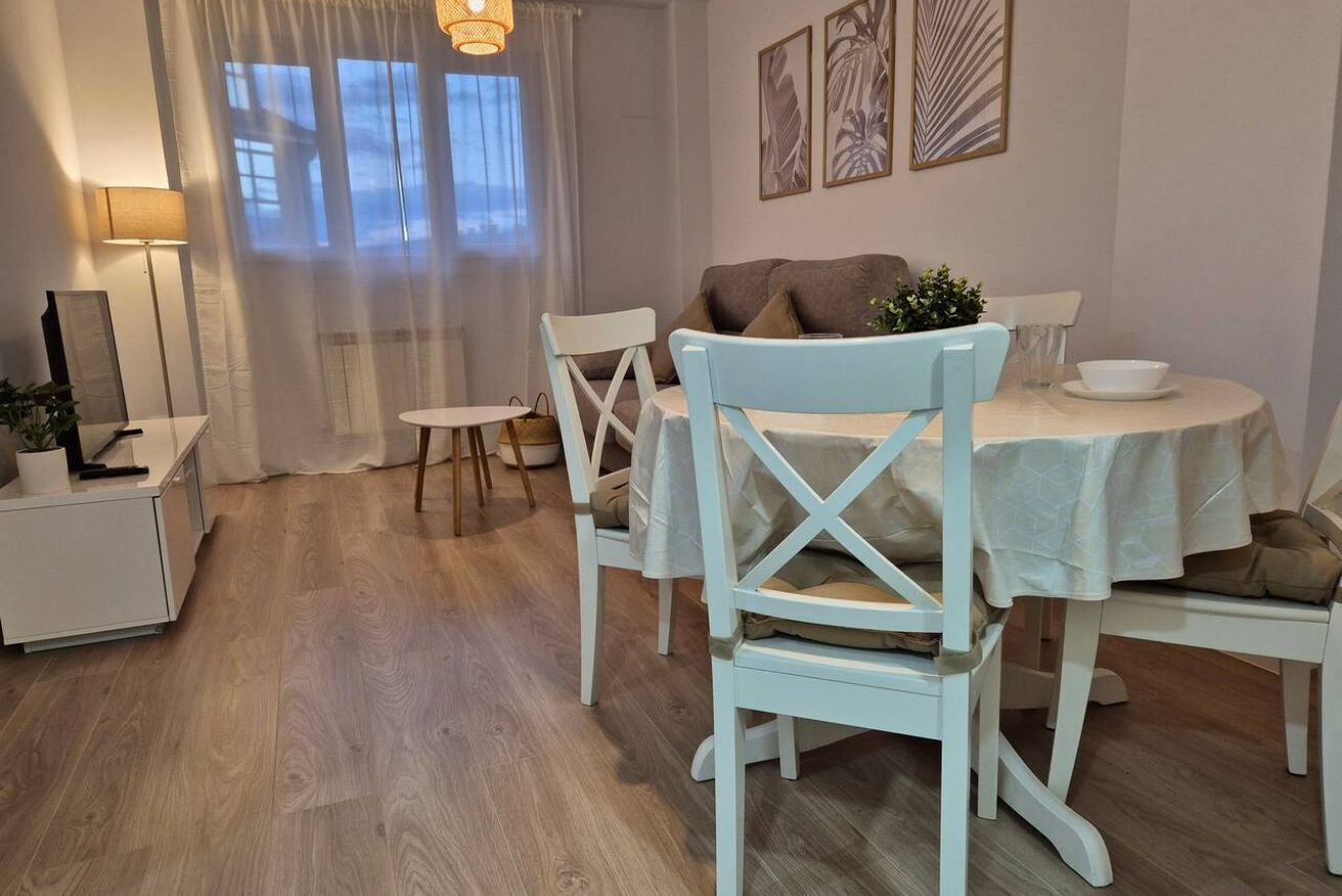 A dining area with a round table, white chairs, a sofa, and a lamp.