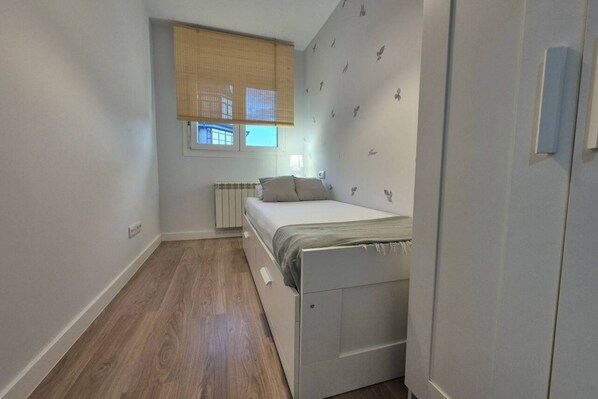 A small bedroom with a bed, a radiator, a window with blinds, and a door. - 650A Apartamento moderno, acogedor y con garaje (Oviedo)