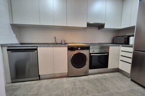A kitchen with a dishwasher, washing machine, oven, and microwave. - 650A Apartamento moderno, acogedor y con garaje (Oviedo)