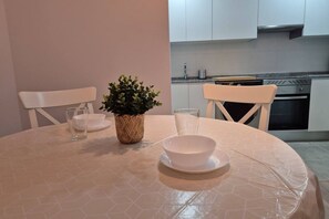 A dining table with a white tablecloth, two white chairs, a potted plant, and a bowl and glass set. - 650A Apartamento moderno, acogedor y con garaje (Oviedo)