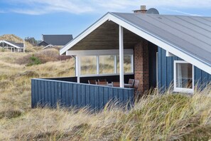 A modern house with a sloped roof, large windows, and a covered outdoor area.