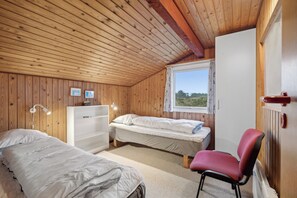 A cozy room with wooden walls, a bed, a desk, and a chair.