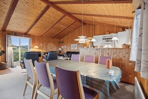 A wooden interior with a dining table, chairs, and a kitchen area.