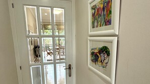 Eine Tür mit Glasfenster und Türgriff. Zwei Bilder hängen an der Wand.