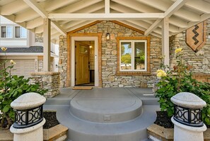 A stone-clad house entrance with a covered porch, a wooden door, and a stone wall with a window.