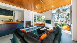 Un salon moderne avec un plafond en bois, une grande fenêtre et un espace cuisine intégré.