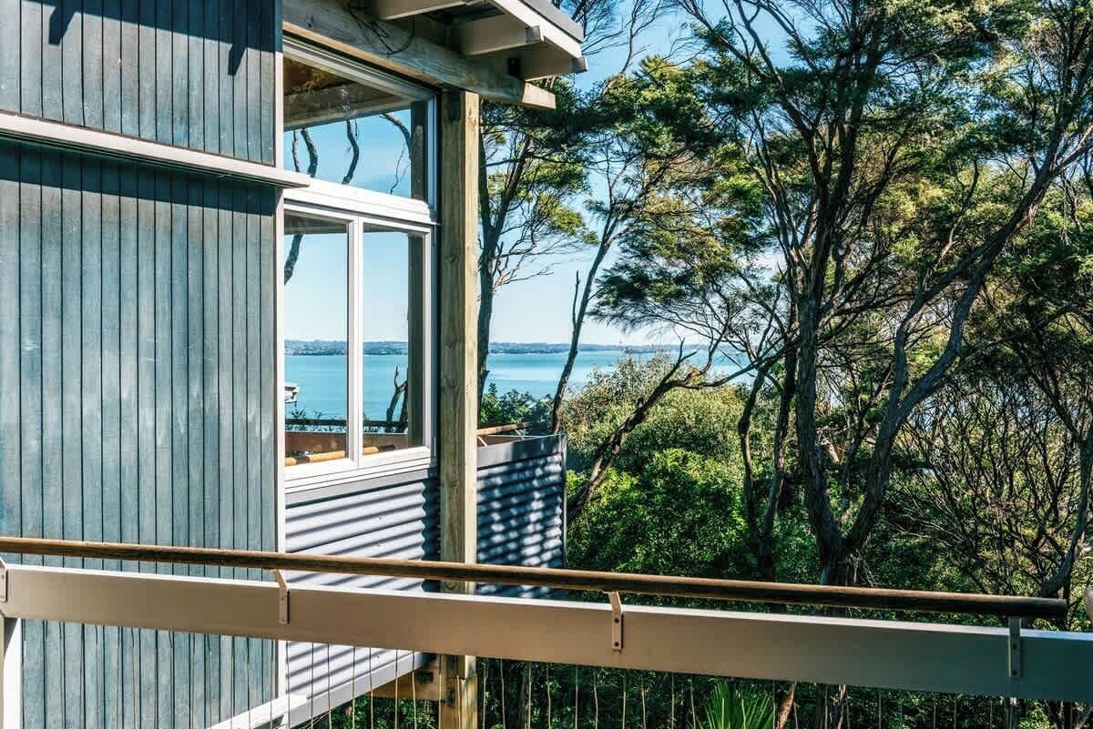 A wooden house with a balcony overlooking a body of water and trees.