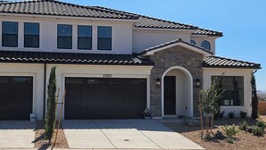 A two-story house with a stone facade, a garage, and a clear view of the surrounding landscape.