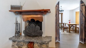 Uma lareira de pedra com proteção de metal, uma moldura de madeira e um rádio em cima.