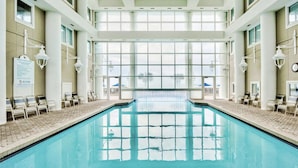 Una amplia piscina cubierta con paredes de vidrio transparente que ofrecen vistas al exterior.