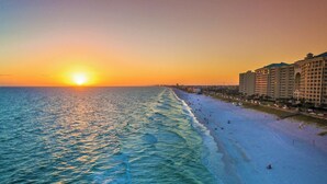 Una playa con un atardecer, un hotel y un paisaje urbano al fondo.