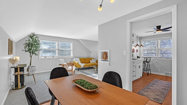 Una cocina moderna con zona de comedor, que incluye una mesa de madera, sillas y un ventilador de techo.