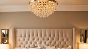 A luxurious bedroom with a tufted headboard, plush bedding, and a chandelier. - Charming 4-bedroom house with WiFi, AC in Kingwood,TX (Humble)