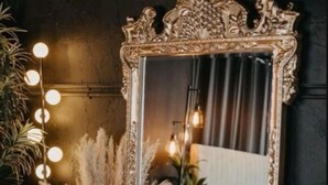 A mirror with an ornate frame, surrounded by decorative plants and a round table with a patterned centerpiece. - Charming 4-bedroom house with WiFi, AC in Kingwood,TX (Humble)