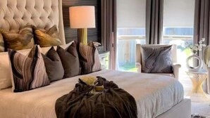 A spacious bedroom with a large bed, a tufted headboard, and a chandelier. - Charming 4-bedroom house with WiFi, AC in Kingwood,TX (Humble)