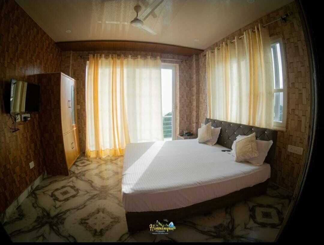 A hotel room with a large bed, curtains, a television, and a patterned floor.