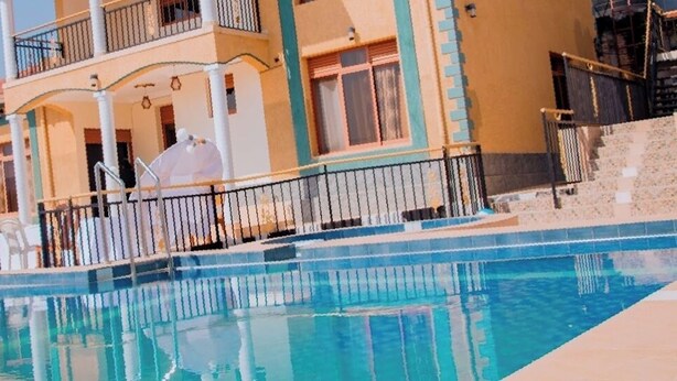 Una piscina con un edificio de dos pisos al fondo.