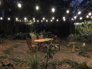 An outdoor dining area with a round table and chairs, surrounded by plants and trees. - Walk to Midtown - Fire, Bikes, Capitol 1M, FSU 2M (Tallahassee)