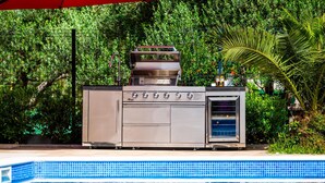A stainless steel outdoor kitchen with a built-in oven and grill, positioned next to a swimming pool. - 6 bedroom amazing home in Bilice (Bilice)