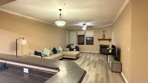 A modern living room with a large L-shaped sectional sofa, a fireplace, and a ceiling fan. - Large 3 Bedroom in Central Scottsdale w/ Pool, Clubhouse, Fitness Room and More… (Scottsdale)