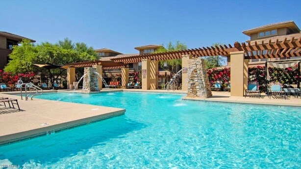 A swimming pool with a pergola and stone pillars, surrounded by lounge chairs and flower beds. - Large 3 Bedroom in Central Scottsdale w/ Pool, Clubhouse, Fitness Room and More… (Scottsdale)
